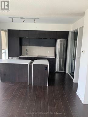 Toronto (Regent Park) condo for rent - A modern kitchen with dark wood floors and white countertops.