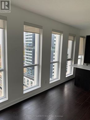 Toronto (Regent Park) condo for rent - A room with a large window overlooking a cityscape.