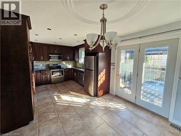 Kitchener apartment for rent - A well-lit kitchen with brown cabinets and a chandelier.