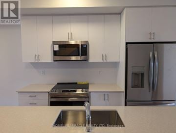 Toronto (Bendale) townhouse for rent - A kitchen with white cabinets and a stainless steel refrigerator.