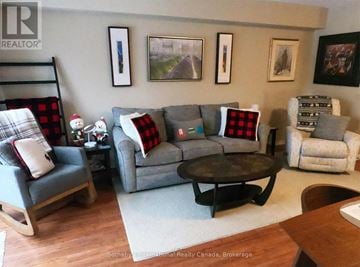 Collingwood townhouse for rent - A living room with a grey couch and a wooden chair.