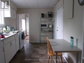 Woodstock (Woodstock - South) apartment for rent - A kitchen with a table and chairs in the foreground and a microwave on the shelves.