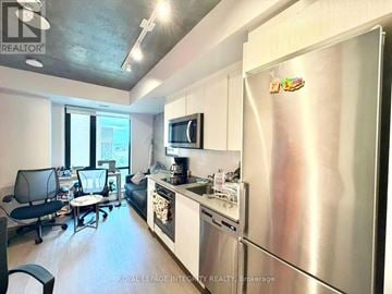 Ottawa condo for rent - A kitchen with a refrigerator, microwave, and a dining table with chairs.