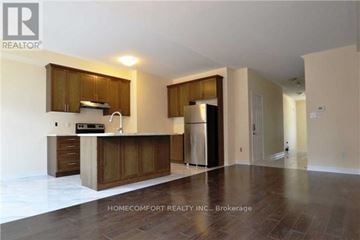Oakville (Go Glenorchy) townhouse for rent - A spacious kitchen with wooden cabinets and a refrigerator.