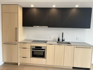 Surrey apartment for rent - A kitchen with wooden cabinets and black countertops.