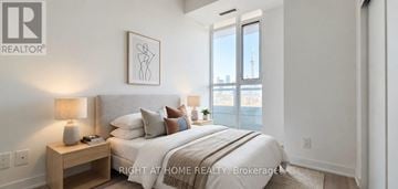 Toronto (Moss Park) condo for rent - A bedroom with a large bed, a nightstand with a lamp, and a framed picture on the wall.