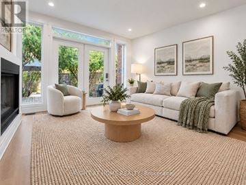 Toronto (Playter Estates-Danforth) apartment for rent - A living room with a white couch, a coffee table, and a fireplace.