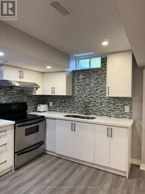 Richmond Hill (Oak Ridges Lake Wilcox) apartment for rent - A kitchen with a black stove top oven and white cabinets.