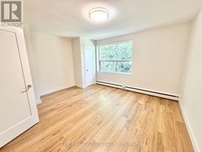 London South (South F) condo for rent - A room with wooden flooring and white walls, with a window showing greenery outside.