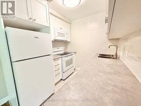 London South (South F) condo for rent - A kitchen with white appliances and a grey floor.
