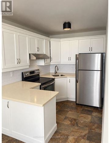 Toronto (Cabbagetown-South St. James Town) condo for rent - A kitchen with white cabinets and a stainless steel refrigerator.