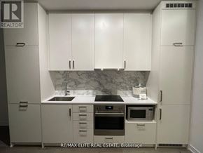 Vaughan (Vaughan Corporate Centre) condo for rent - A kitchen with white cabinets and a marble backsplash.