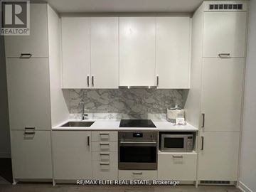 Vaughan (Vaughan Corporate Centre) condo for rent - A kitchen with white cabinets and a marble backsplash.