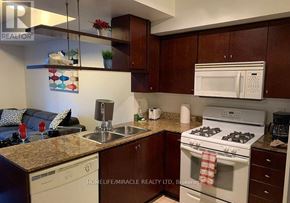 Toronto (Waterfront Communities) condo for rent - A kitchen with a white stove top oven and a white microwave above the counter.