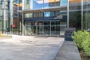 Toronto (Church-Yonge Corridor) condo for rent - The entrance to a building with a glass facade and a stone pillar with the number 55 on it.