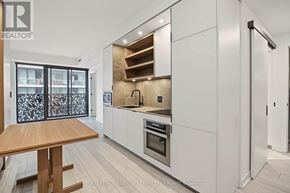 Toronto (Church-Yonge Corridor) condo for rent - A modern kitchen with white cabinets and a wooden table.