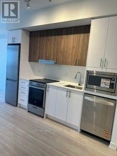 Mississauga (City Centre) condo for rent - A modern kitchen with white cabinets and stainless steel appliances.