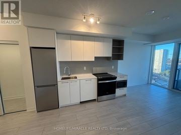 Brampton (Fletcher's Creek South) condo for rent - A kitchen with white cabinets and a black fridge.