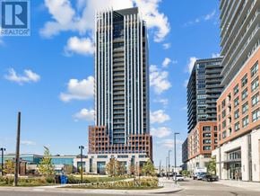 Toronto (Leaside) condo for rent - A tall building stands in the middle of a city street.