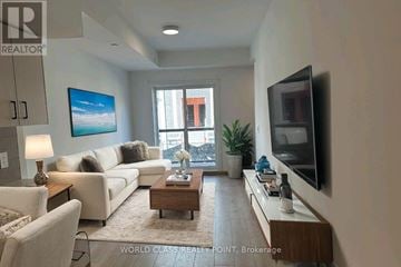 Toronto (Tam O'shanter-Sullivan) townhouse for rent - A living room with a white couch, a wooden coffee table, and a flat-screen TV mounted on the wall.