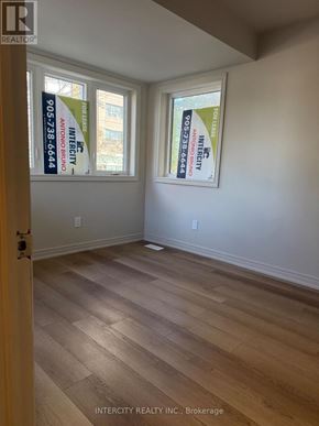 Toronto (Oakwood Village) apartment for rent - A room with wood flooring and two windows with Intercity Realty posters on them.