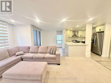 Toronto (Agincourt South-Malvern West) condo for rent - A spacious living room with a large sectional sofa and a kitchen area in the background.