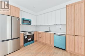 Toronto (Dovercourt-Wallace Emerson-Junction) townhouse for rent - A kitchen with wooden cabinets and a stainless steel refrigerator.