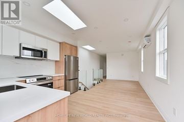 Toronto (Dovercourt-Wallace Emerson-Junction) townhouse for rent - A kitchen with white cabinets and a wooden floor.