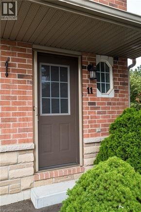 Stoney Creek townhouse for rent - A brown door with a window above it and a small bush to the right.