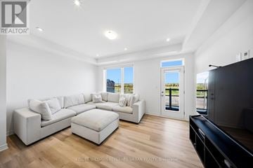 Barrie townhouse for rent - A spacious living room with a white sofa set and a black television.