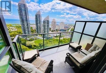 Toronto (Mimico) condo for rent - A balcony with two chairs and a table overlooking a cityscape.