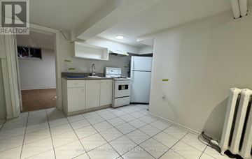 Toronto (Briar Hill-Belgravia) apartment for rent - A kitchen with white cabinets and appliances in a room with white walls and tile flooring.