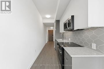 Kitchener condo for rent - A modern kitchen with white cabinets and a black microwave.