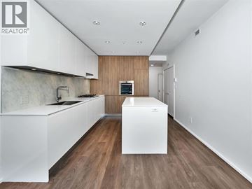 Burnaby apartment for rent - A modern kitchen with white cabinets and a wooden accent wall.
