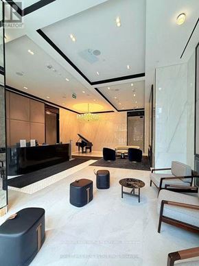 Toronto (Bay Street Corridor) condo for rent - A spacious lobby with a piano, chairs, and a reception desk.