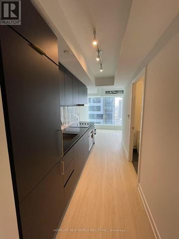 Toronto (Bay Street Corridor) condo for rent - A modern kitchen with dark brown cabinets and a wooden floor.