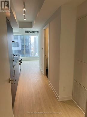 Toronto (Bay Street Corridor) condo for rent - A long hallway with wood floors and white walls.