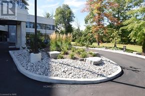 Niagara Falls (Oldfield) condo for rent - A landscaped area in front of a building with a sign that says "REALTOR".