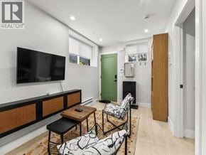Vancouver apartment for rent - A living room with a television, a green door, and a black and white rug.