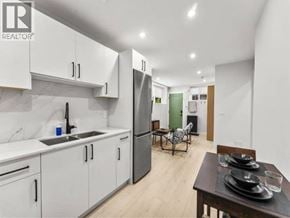 Vancouver apartment for rent - A modern kitchen with white cabinets and a wooden table.