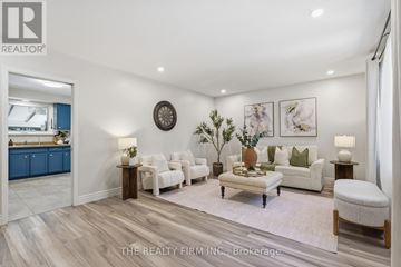 London East (East C) apartment for rent - A well-lit, spacious living room with a white sofa set, a coffee table, and a large clock on the wall.