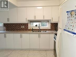 Toronto (Hillcrest Village) apartment for rent - A kitchen with white cabinets and a brown backsplash.