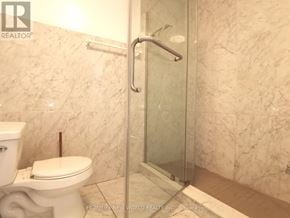 Toronto (Hillcrest Village) apartment for rent - A white toilet sits next to a walk-in shower with a glass door.