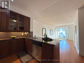 Markham (Unionville) condo for rent - A kitchen with dark wood cabinets and a black countertop.
