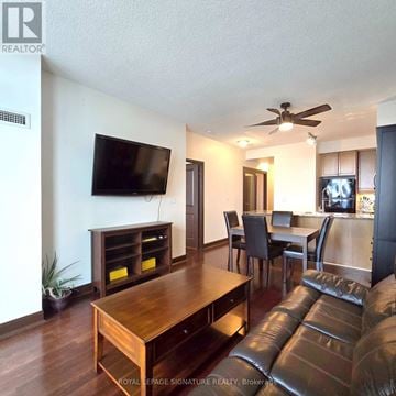 Mississauga (City Centre) condo for rent - A living room with a brown leather couch and a wooden table.