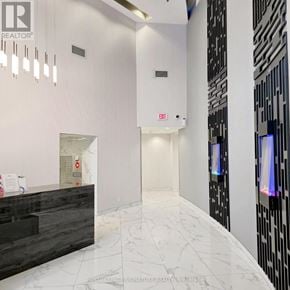 Mississauga (City Centre) condo for rent - A white hallway with a black reception desk and a red exit sign.