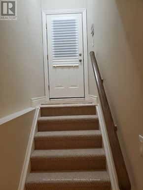 Toronto (Englemount-Lawrence) apartment for rent - A staircase with beige carpeted steps leading to a white door with a window above it.