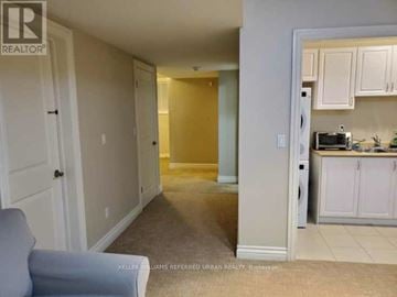 Toronto (Englemount-Lawrence) apartment for rent - A living room with a grey couch and a kitchen area in the background.