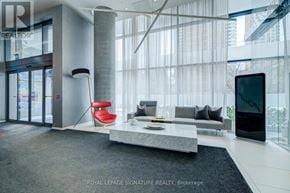 Toronto (Mount Pleasant West) condo for rent - A modern living room with a glass door entrance and a red chair.