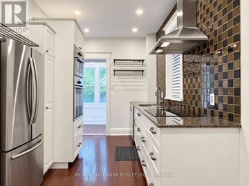 Toronto (Greenwood-Coxwell) apartment for rent - A kitchen with white cabinets and a stainless steel refrigerator.